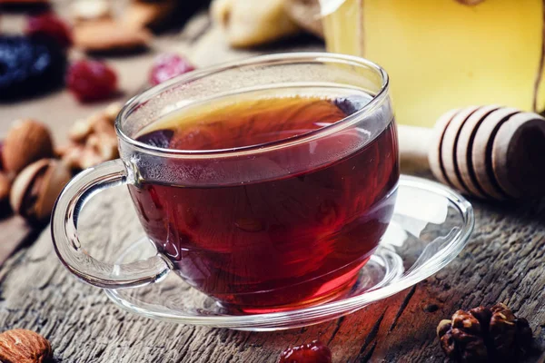 Μαύρο τσάι σε ένα φλιτζάνι γυαλί με μέλι, αποξηραμένα φρούτα και ξηρούς καρπούς — Φωτογραφία Αρχείου
