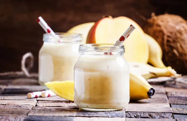 Banana mango smoothie with coconut in a glass jars — Stock Photo, Image