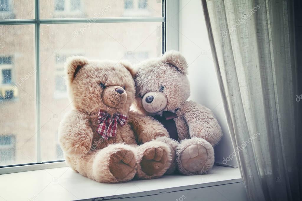 Brown teddy bears on the window on a rainy day