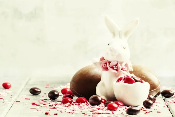 Porcelain Easter bunny with brown and red chocolate eggs — Stock Photo, Image