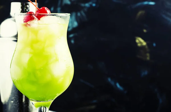 Green cocktail with maraschino cherries