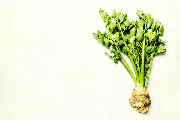 Raw root celery with green stems 