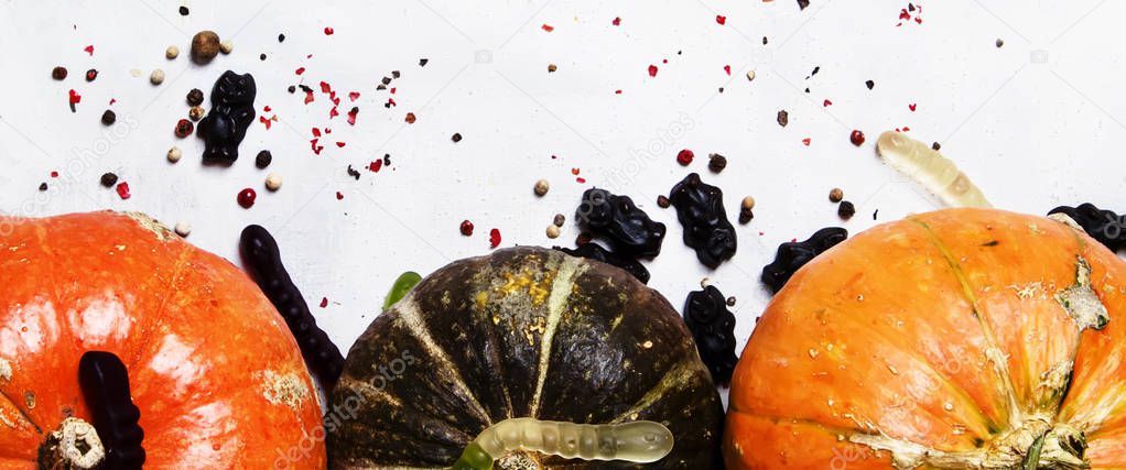 Halloween background, pumpkins, worms and black candies