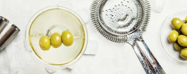 Klasik alkollü kokteyl kuru vermut ve araçları, gri arka plan, üstten görünüm bar yeşil zeytin ile