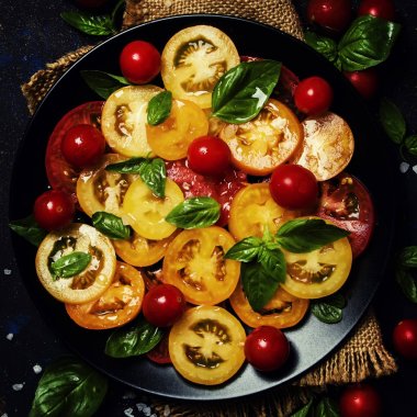 Bahar salatası domates, mozzarella peyniri ve yeşil fesleğen, koyu arka plan, üstten görünüm