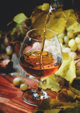 Cam, üzüm ve asma, Vintage ahşap arka plan, seçici odak konyak Pour