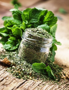 Bir cam kavanoz ve bir demet taze nane, vintage ahşap arka plan, seçici odak kuru nane