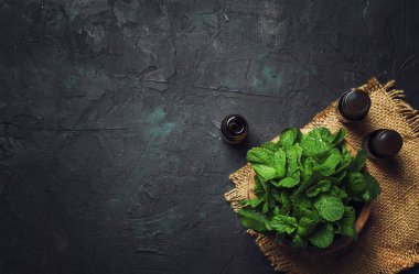 Nane taze yeşil nane, siyah arka plan, üstten görünüm ile küçük bir kahverengi şişe içinde uçucu yağ