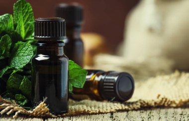 Nane taze yeşil nane, rustik tarzı, vintage ahşap arka plan, seçici odak ile küçük bir kahverengi şişe içinde uçucu yağ