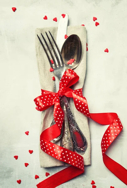 カトラリー 赤いリボン 甘い心 灰色背景の平面図 バレンタインデーのお祝いテーブル設定設定 — ストック写真