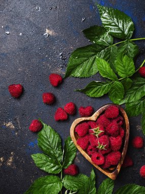 Taze pembe Ahududu ve koyu arka plan, üstten görünüm üzerinde yeşil yaprakları ile kase