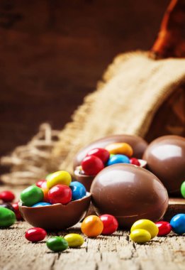 Çikolata yumurta ve renkli şeker, vintage ahşap arka plan, seçici odak ile Paskalya kompozisyon