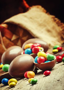 Çikolata yumurta ve renkli şeker, vintage ahşap arka plan, seçici odak ile Paskalya kompozisyon