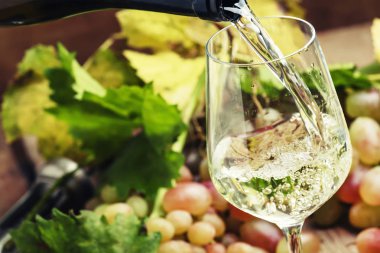 White wine being poured into a glass, vintage wood background, selective focus clipart