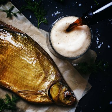 Altın füme nehir çipura ve siyah bira koyu arka plan, üstten görünüm