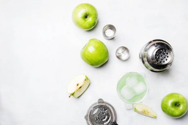 Alkollü kokteyl yeşil elma ve kuru vermut, şurup, limon suyu ve buz küpleri ile. Görünümü araçları, gri taş zemin, top