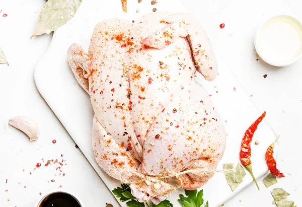 Raw whole chicken with spices and marinade, gray background, top view