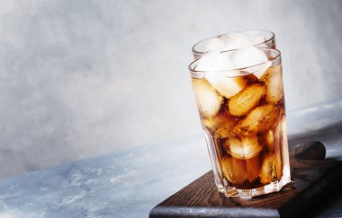 Alkollü kokteyl rom-kola buz, gri arka plan, seçici odak ile