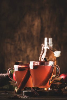 Ahşap zemin üzerinde tarçın çubukları, karanfiller ve anasonlu sıcak elma sirkesi. Geleneksel sonbahar, kış içkileri ve kokteyller