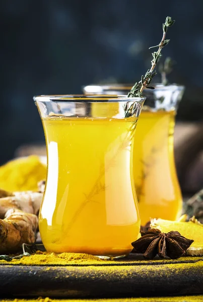 Healthy vegan turmeric golden tea with honey in glass cup on wooden tray. Herbal healing spicy tea