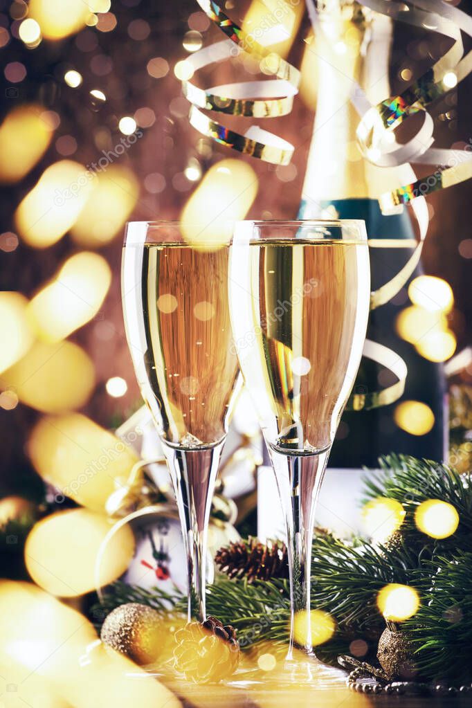 Two champagne glasses and christmas decoration on wooden snow golden bokeh background. Happy New Year Celebration. Selective focus and small depth of field