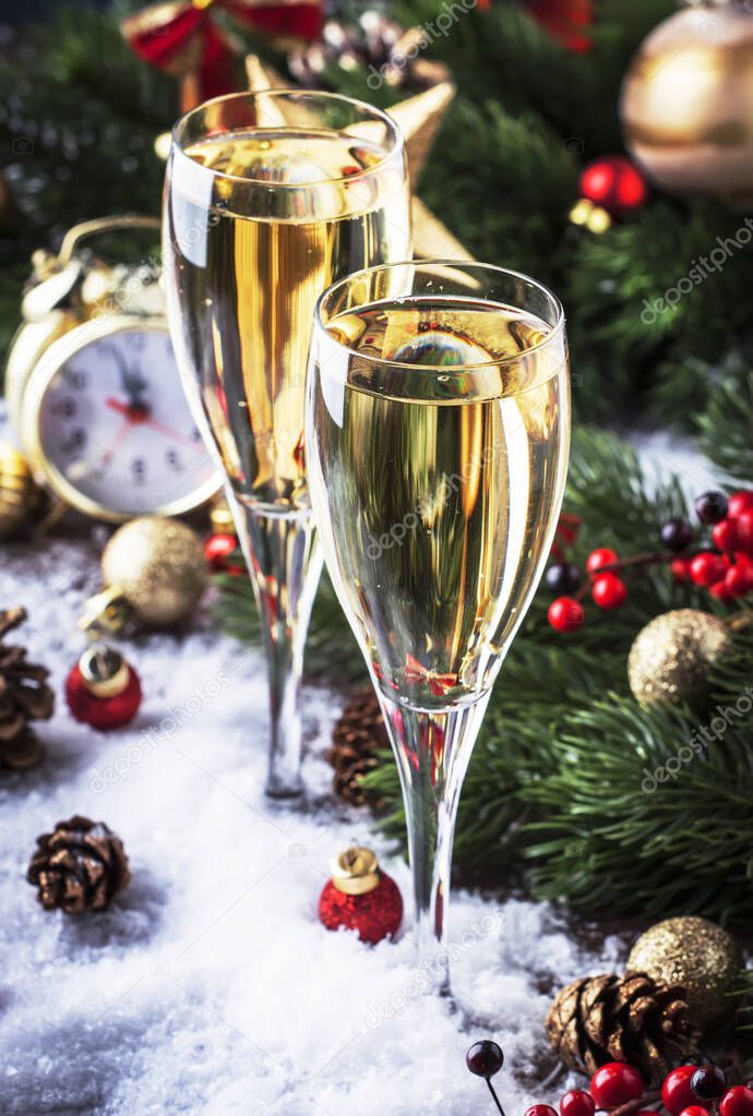 Two champagne glasses and christmas decoration over blue snow golden bokeh background. Happy New Year Celebration. Selective focus and small depth of field