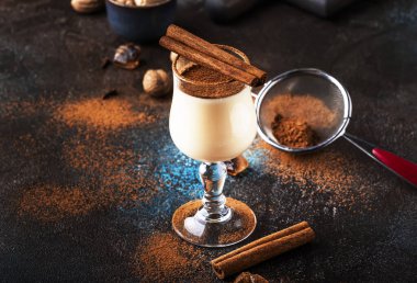 Eggnog kokteyl sıcak kış veya süt, yumurta ve koyu rom ile sonbahar içki, tarçın ve mavi koyu arka plan üzerinde shot cam hindistan cevizi serpilir, kopya alanı