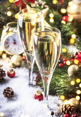 Mavi kar ve altın bokeh arka planda iki şampanya bardağı ve noel süslemesi. Mutlu yeni yıl kutlamaları. Seçici odak ve küçük alan derinliği