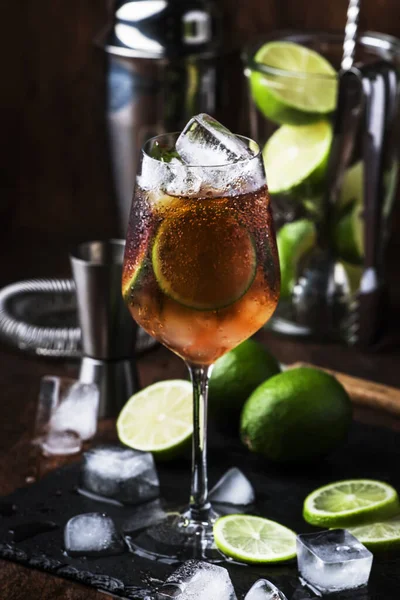 Alcoholic cocktail Long Island with vodka, gin, tequila silver, white rum, liqueur, sugar syrup, lemon juice, cola and ice cubes, vintage bar wooden counter background, selective focus