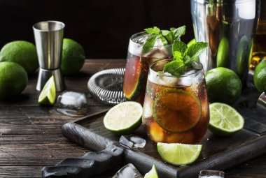 Altın rom ile Küba libre alkol kokteyl, limon suyu, kola, kireç ve buz, koyu bar sayacı arka plan, bar araçları, metin için yer