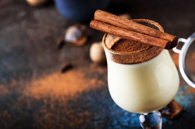 Eggnog kokteyl sıcak kış veya süt, yumurta ve koyu rom ile sonbahar içki, tarçın ve mavi koyu arka plan üzerinde shot cam hindistan cevizi serpilir, kopya alanı