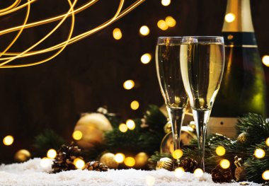 İki şampanya bardağı ve ahşap kar, altın bokeh arka planda noel süsü. Mutlu yeni yıl kutlamaları. Seçici odak ve küçük alan derinliği