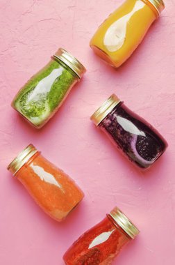 Çok renkli Detoks vegan sebze suları ve kopyalama alanı, top görünümü smoothies pembe tablo, pişmemiş yiyecek ve temiz gıda kavramı, içki arka plan, cam şişelerde