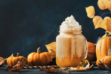 Balkabağı aromalı latte ya da mavi masadaki cam bardakta kahve. Sonbahar ya da kış sıcak içeceği şenlikli doğal masa ortamında.