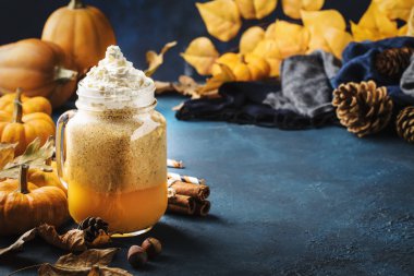 Balkabağı aromalı latte ya da mavi masadaki cam bardakta kahve. Sonbahar ya da kış sıcak içeceği şenlikli doğal masa ortamında.
