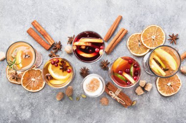 Çeşitli sonbahar veya kış mevsimsel alkol sıcak kokteylleri - sıcak şarap, glogg, grog, eggnog, sıcak zencefilli gazoz, sıcak tereyağlı rom, punç, gri arka planda sıcak elma şarabı, fotokopi alanının üst görüntüsü