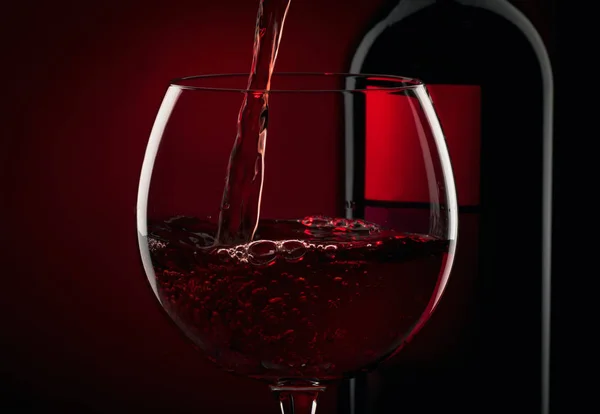 Despejar Vinho Tinto Copo Contra Fundo Preto Vermelho — Fotografia de Stock