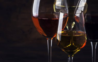 Şarap tatma konsepti, durgun ve köpüklü şaraplar. Kırmızı, beyaz şarap, gül ve şampanya şarap kadehleri eski ahşap masa arka planında