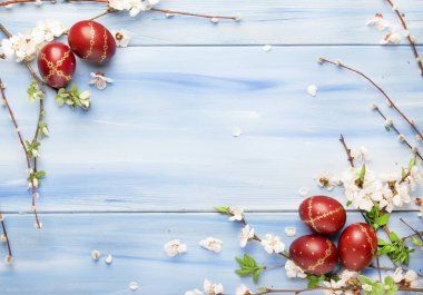 Paskalya yumurtaları ve bahar çiçekleri ve söğüt dalları. Paskalya mavisi ahşap arka planda. Kopya alanı olan.