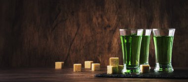 Absinthe-güçlü alkollü içecek, eski ahşap masada gözlük yeşil acı pelin tentür, metin için yer