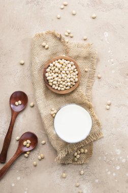 Bej arka planda soya sütü ve soya fasulyesi. Süt içermeyen alternatif süt konsepti. Vejetaryen içeceği. Boşluğu kopyala