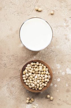 Bej arka planda soya sütü ve soya fasulyesi. Süt içermeyen alternatif süt konsepti. Vejetaryen içeceği. Boşluğu kopyala