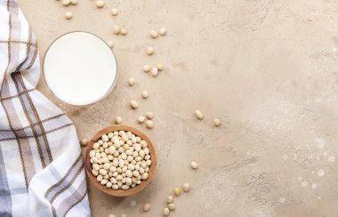 Bej arka planda soya sütü ve soya fasulyesi. Süt içermeyen alternatif süt konsepti. Vejetaryen içeceği. Boşluğu kopyala
