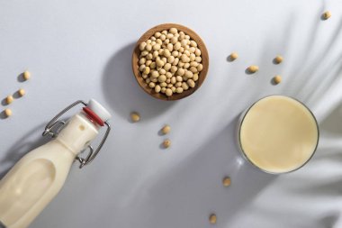 Mutfak arka planında soya sütü ve soya fasulyesi. Sütsüz süt konsepti. Vejetaryen içkisi. Sert ışık. Boşluğu kopyala