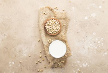 Bej arka planda soya sütü ve soya fasulyesi. Süt içermeyen alternatif süt konsepti. Vejetaryen içeceği. Boşluğu kopyala