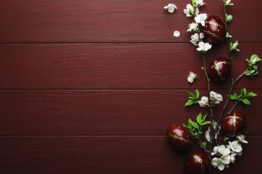 Easter eggs and spring white flowers on Easter red wood background with copy space