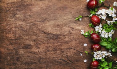 Easter eggs and spring white flowers and willow branches on Easter wooden background with copy space