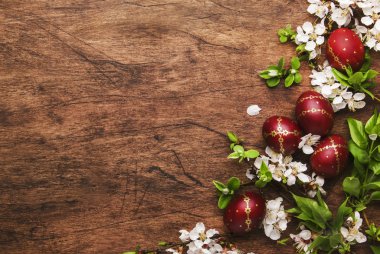 Easter eggs and spring white flowers and willow branches on Easter wooden background with copy space