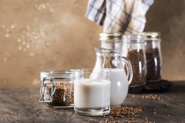 Vegan Buckwheat plant based milk in bottles, closeup, brown background. Non dairy alternative milk. Healthy vegetarian food and drink concept. Copy space