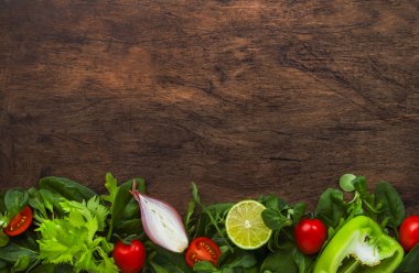 Healthy food background with various green herbs and vegetables. Ingredients for cooking salad. Vegetarian and vegan food concept. Top view, wooden frame with copy space